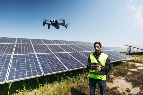 operador voando drone em usina fotovoltaica para inspeção de painéis solares